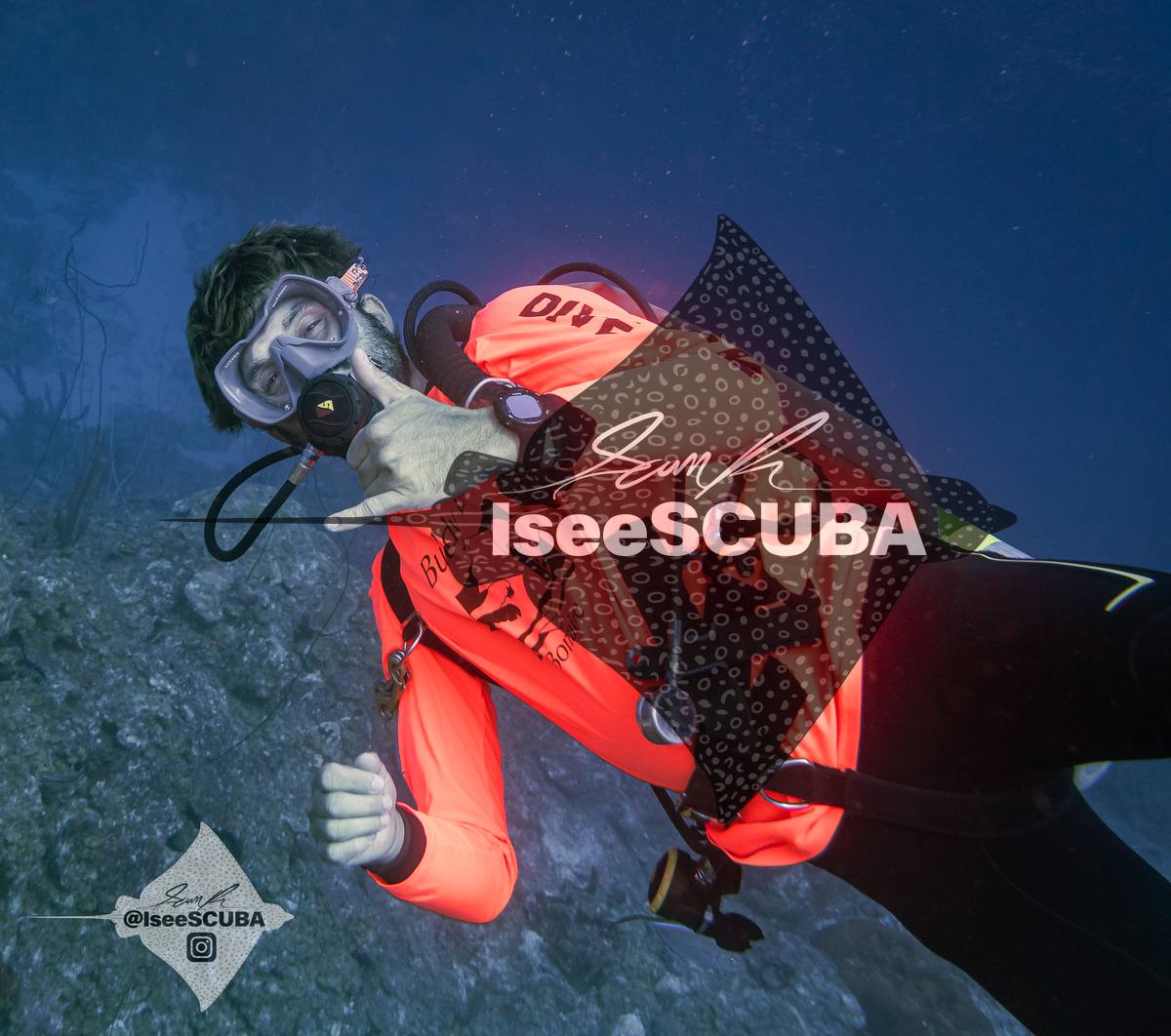 Diver in a bright orange top gesturing toward the camera.
